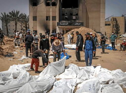 Trabajadores de Defensa Civil, con los cuerpos exhumados en las fosas del hospital Nasser.