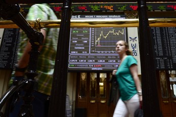 Una mujer pasa ante las pantallas de la Bolsa de Madrid. (Javier SORIANO/AFP PHOYO)