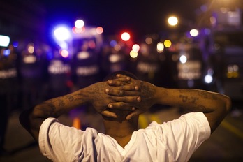 Un manifestante arrodillado frente a las fuerzas policiales. (Mark MAKELA / AFP)