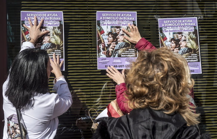 Dos trabajadoras ponen carteles para denunciar su situación. (Marisol RAMÍREZ / FOKU)