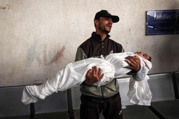 Un hombre llora con el cadáver de su hija en brazos.